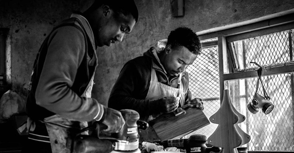 The Coco Africa team of artisans in their workshopcrafting their wooden home and kitchen products. Coco Africa wooden home décor products are available at Sarza home goods and furniture store in Rye New York
